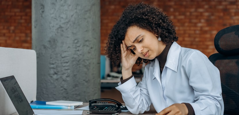 Eine Frau sitzt am Laptop und denkt über ihr Stressmanagement nach.